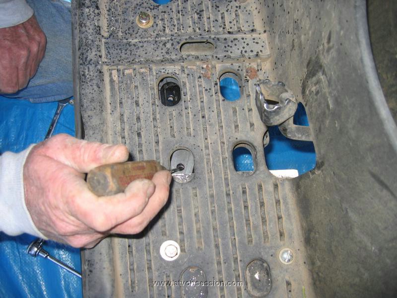 08. Step 6. Use a small screw driver to help guide the plate into position between the metal brace and the plastic footwell..jpg